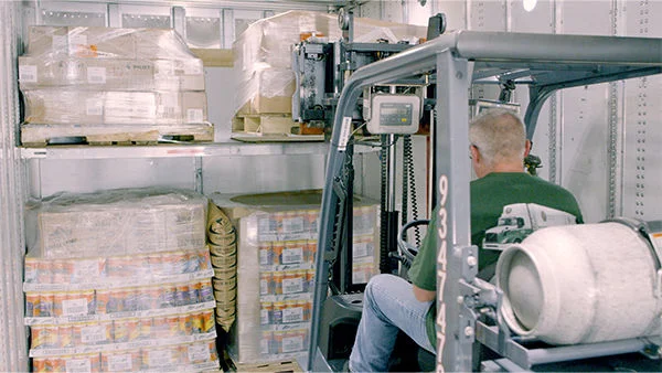 ODFL employee operating forklift to load palletized freight inside a trailer.