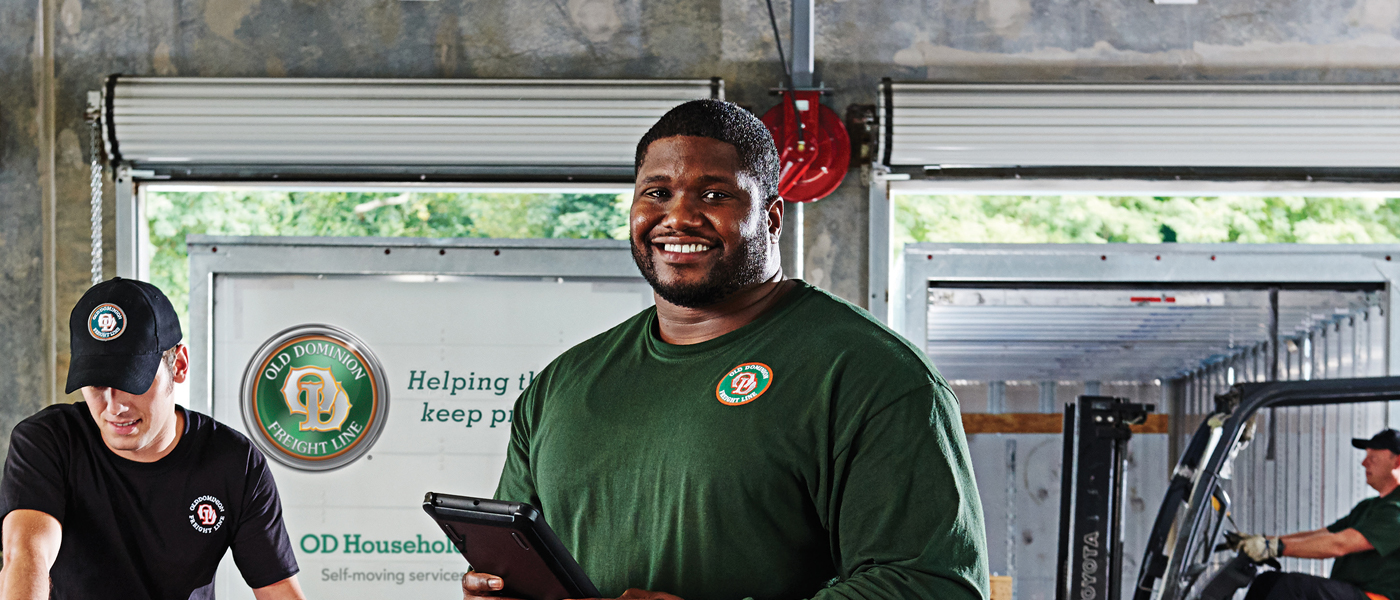 Old Dominion Freight Line employee holding a tablet in a warehouse, representing weekend delivery services.
