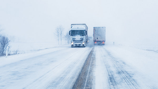 Freight transportation truck on the road in snow storm blizzard, bad weather conditions for transportation event, selective focus