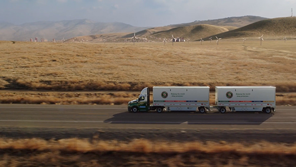 Truck with two trailers driving through a desert with wind turbines, representing Mexico LTL and truckload freight.